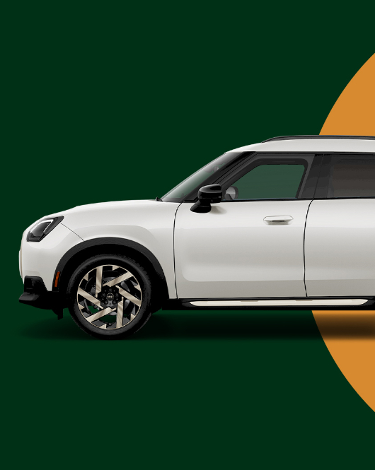 Side view of a white MINI Countryman on a green background with an orange circle behind the vehicle.